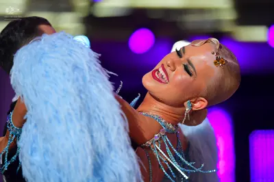 Dancesport competitor: Female dancer: Light blue costume featuring a large light blue feather boa and b