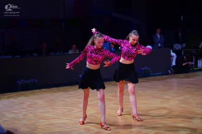 Dancesport competitor: Both dancers: matching long-sleeved tops with a pink and black pattern and short