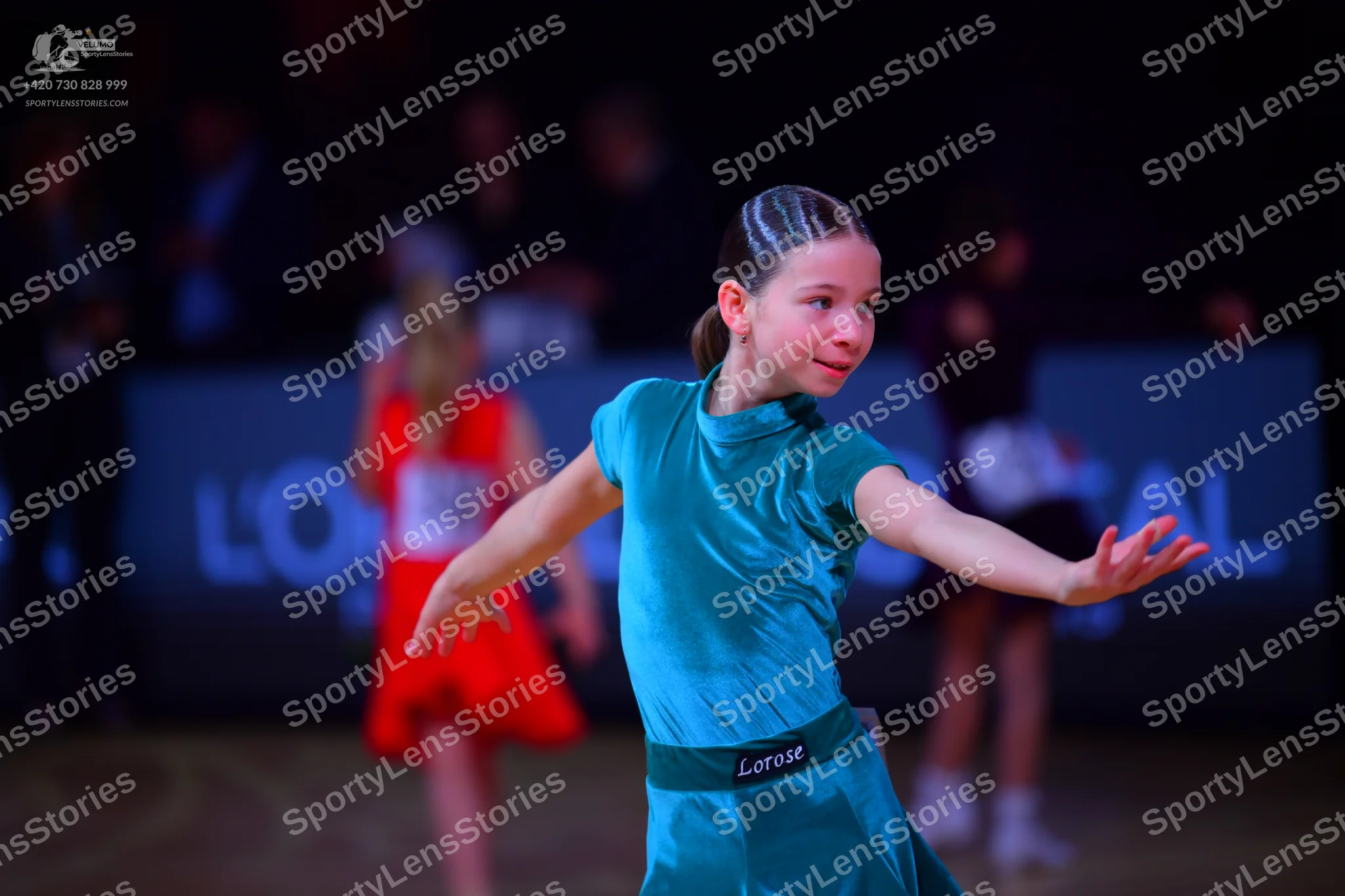 Dancesport competitor: Female dancer in foreground: teal satin dress with short sleeves