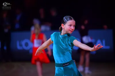 Dancesport competitor: Female dancer in foreground: teal satin dress with short sleeves