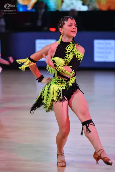 Dancesport competitor: Female dancer: black and neon yellow/lime green Latin dance costume with fringe,