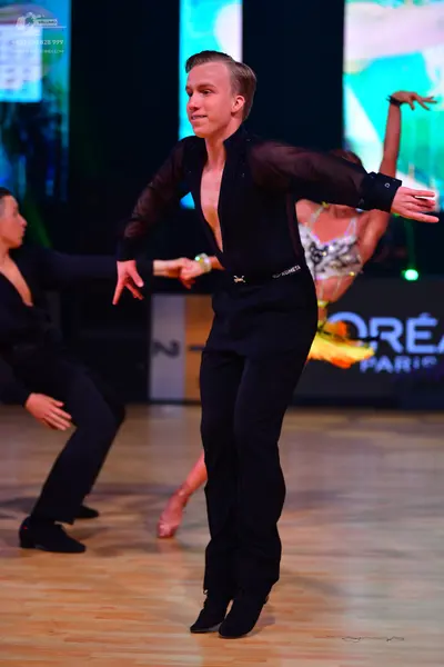 Dancesport competitor: Male dancer 1: black long-sleeved shirt with sheer sleeves and black trousers
