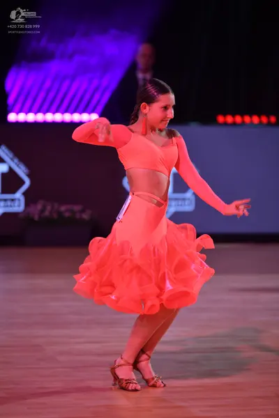 Dancesport competitor: Female dancer: peach-colored Latin dance dress with long sleeves, a cropped bodi
