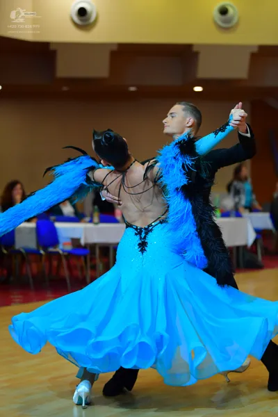 Dancesport competitor: Female dancer: bright blue ballgown with a large, ruffled skirt, black lace/bead