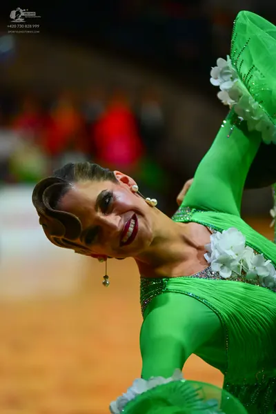 Dancesport competitor: Female dancer: bright green long-sleeved Latin dance dress with ribbed fabric, w
