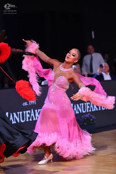 Dancesport competitor: Female dancer: pink Latin dress with sequins and pink feather detailing on the s