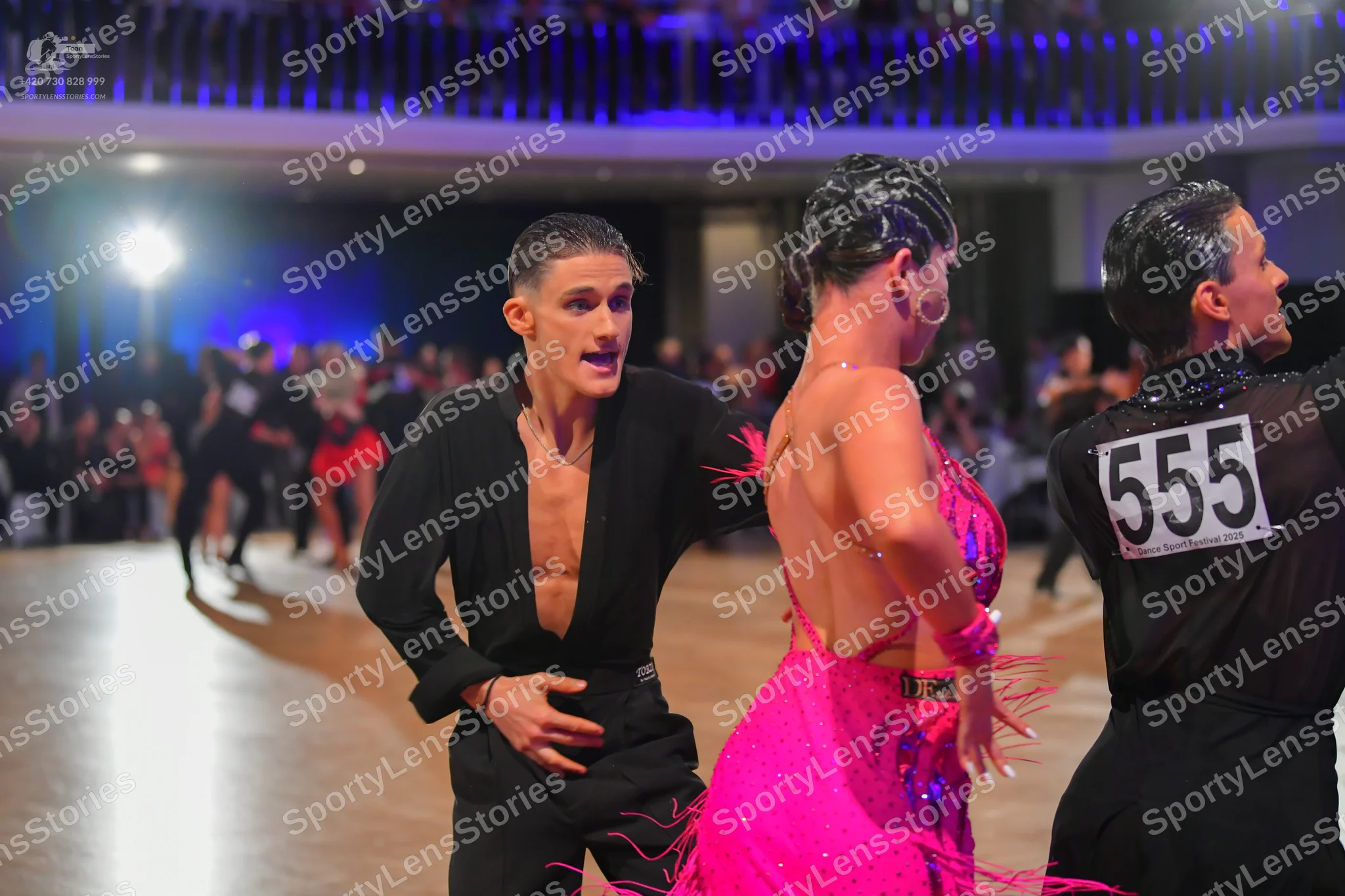 Dancesport competitor #555: Male dancer (left): black Latin dance top, open at the chest, and black trousers