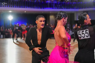 Dancesport competitor #555: Male dancer (left): black Latin dance top, open at the chest, and black trousers