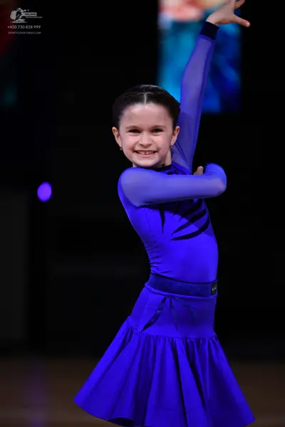 Dancesport competitor: Female dancer: blue long-sleeve Latin dress with dark blue/black patterns on the