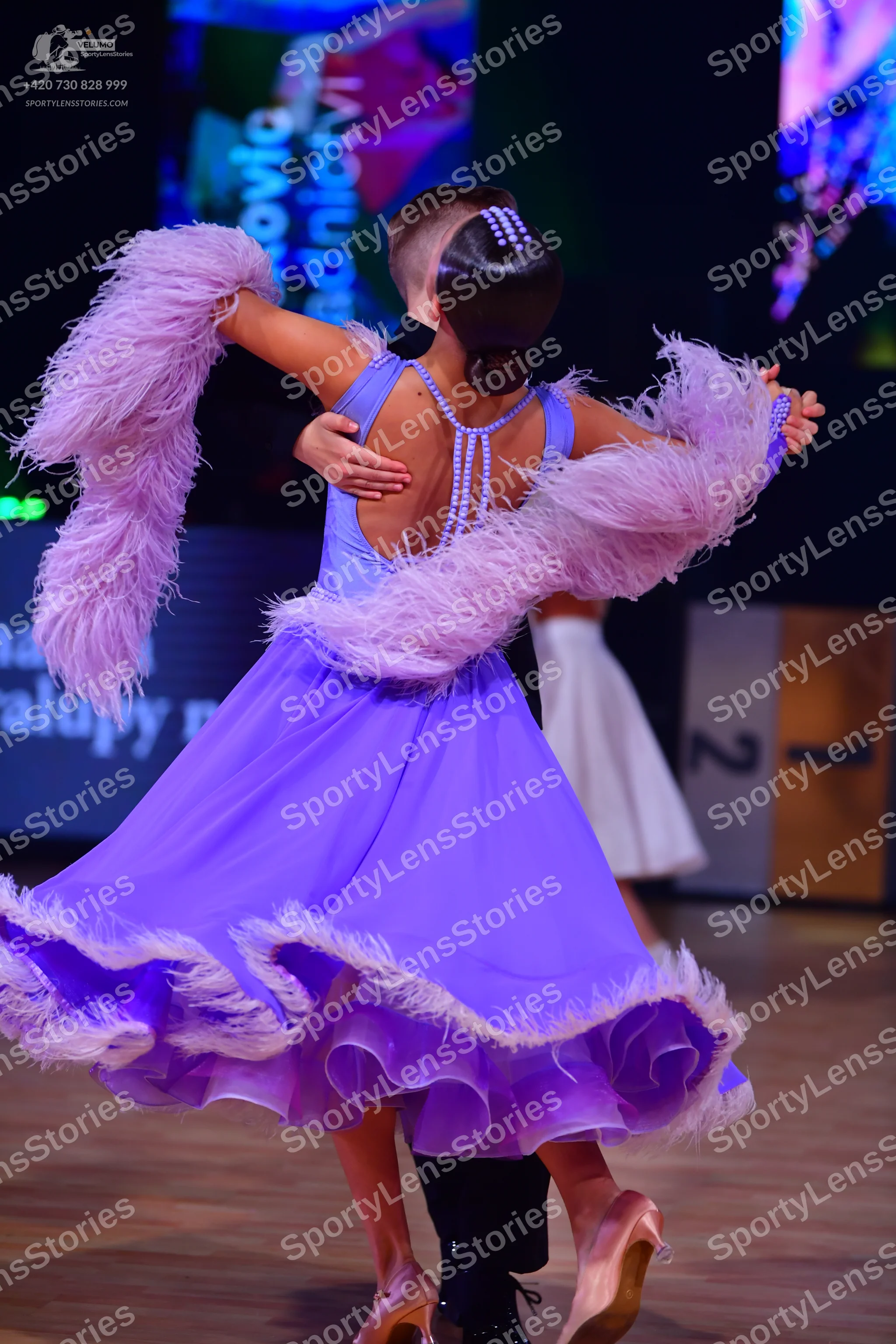Dancesport competitor: Female dancer: light purple Latin dress with large ruffles and white feather tri
