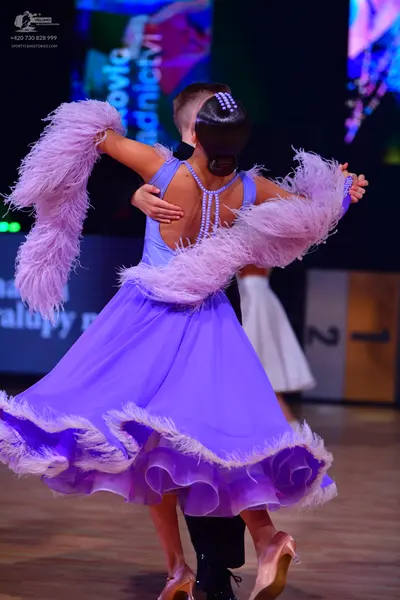 Dancesport competitor: Female dancer: light purple Latin dress with large ruffles and white feather tri