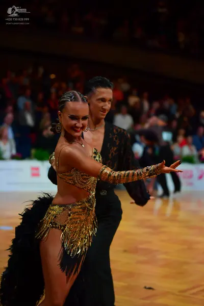 Dancesport competitor: Female dancer: gold sequined latin dress with long black fringe and large hoop e