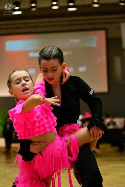 Dancesport competitor: Female dancer: bright pink Latin dance dress with ruffled bodice and long fringe