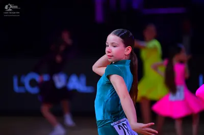 Dancesport competitor: Female dancer in foreground: teal satin Latin dress with short sleeves