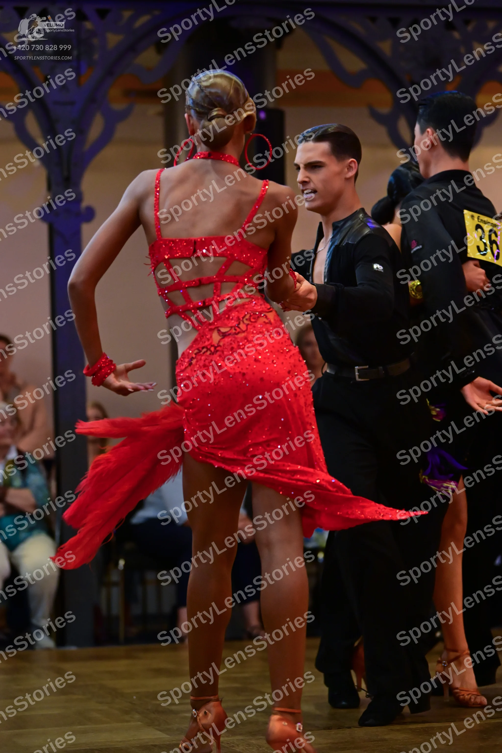 Dancesport competitor: Female dancer: red sequin latin dress with mesh panels, a red wristband, and tan