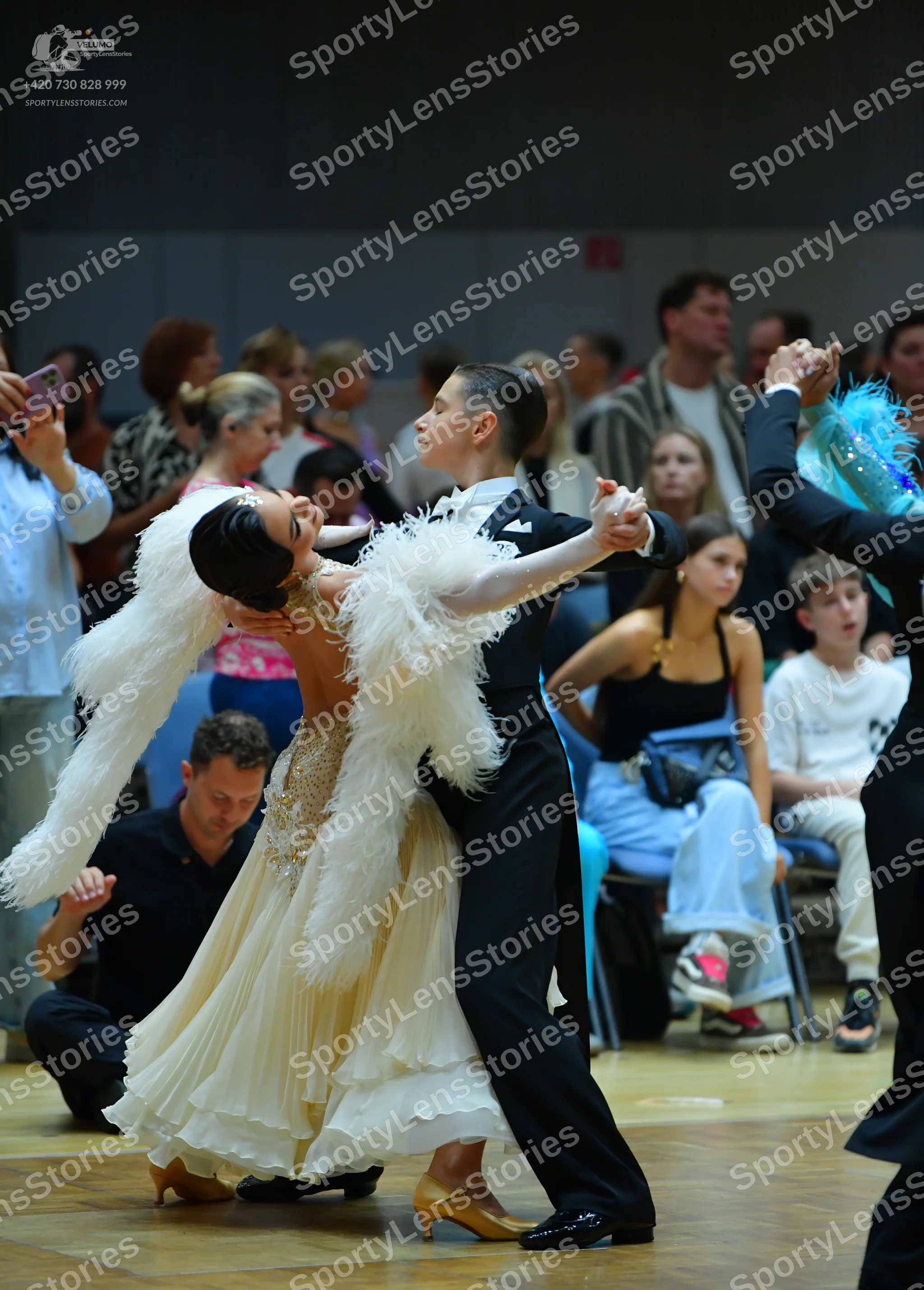 Dancesport competitor: Female dancer: cream-colored ballroom gown with a sequined bodice and large whit
