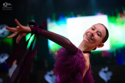 Dancesport competitor: Female dancer: dark purple/plum-colored Latin-style dress with long sleeves and 