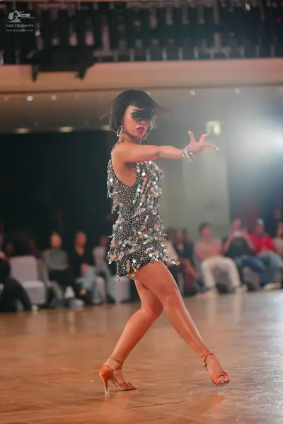 Dancesport competitor: Female dancer: silver sequin Latin dress featuring large metallic discs, accesso
