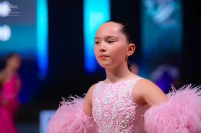 Dancesport competitor: Female dancer in foreground: light pink sleeveless costume decorated with white 