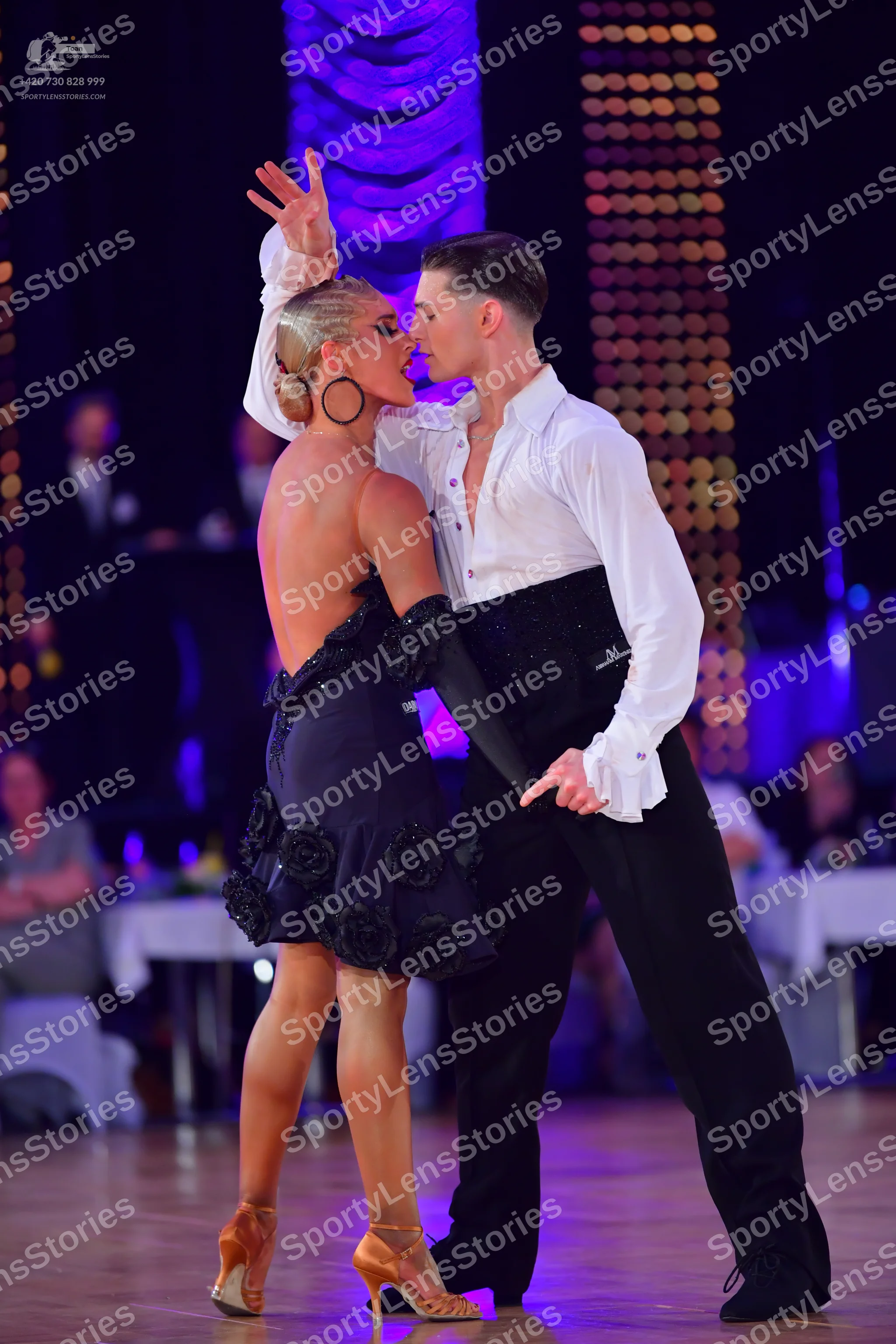 Dancesport competitor: Female dancer: black latin dress with textured floral-like details and a long bl