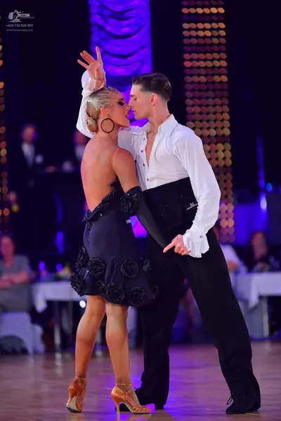 Dancesport competitor: Female dancer: black latin dress with textured floral-like details and a long bl