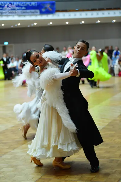 Dancesport competitor: Female dancer: white ballgown with large white feather trim on the bodice and a 