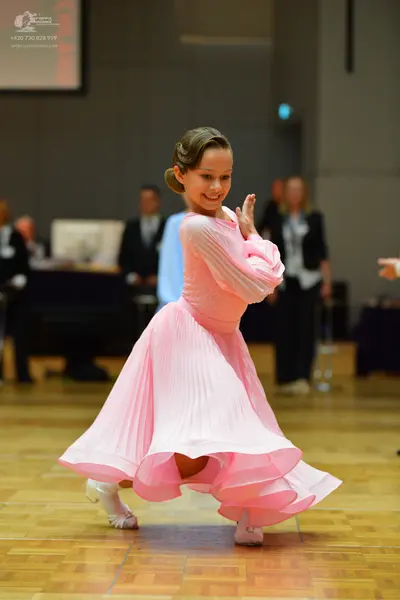 Dancesport competitor: Female dancer: light pink, long-sleeved ballroom dress with a flowing, pleated s