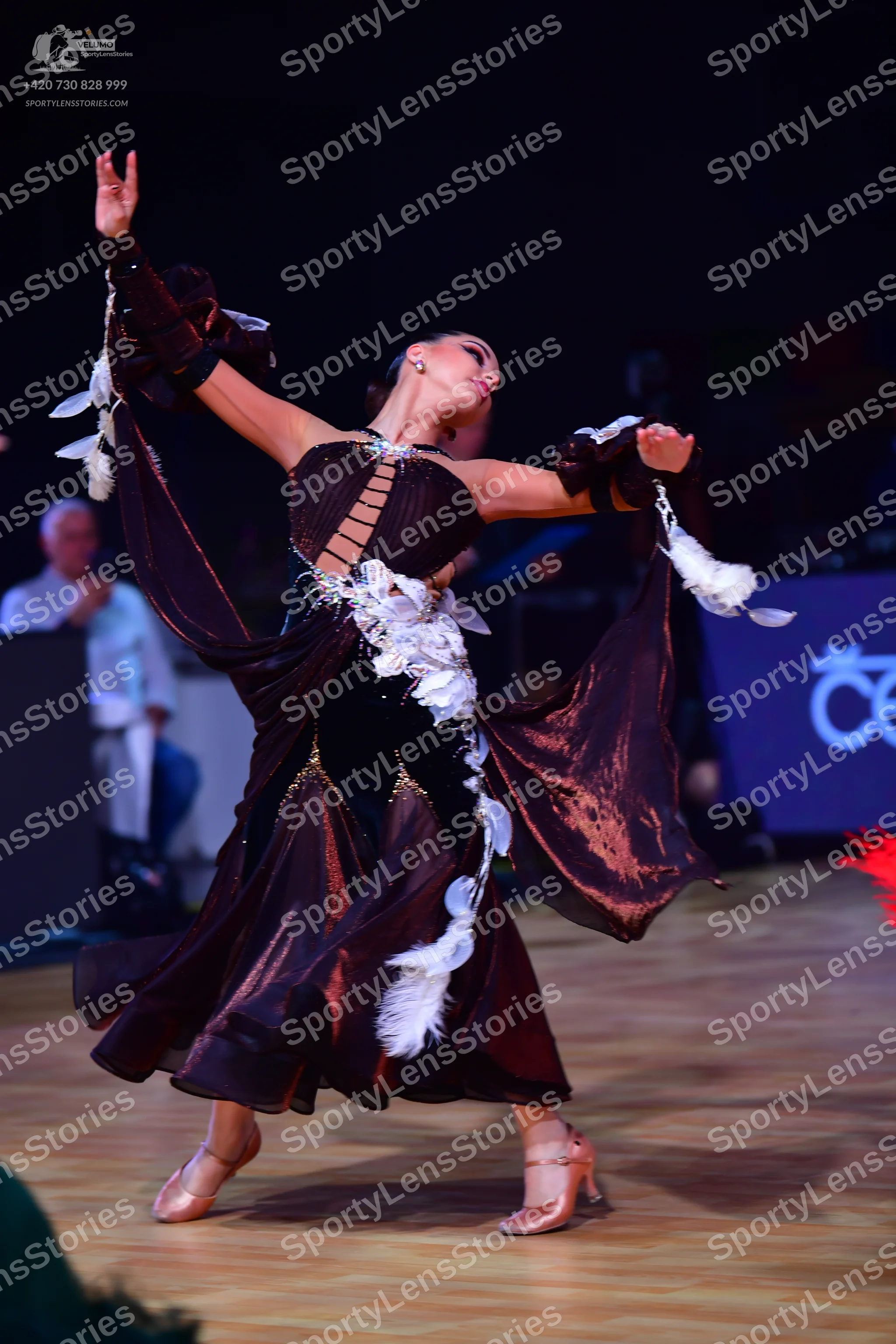 Dancesport competitor: Female dancer: dark brown Latin dance dress with long flowing sleeves, lattice-s