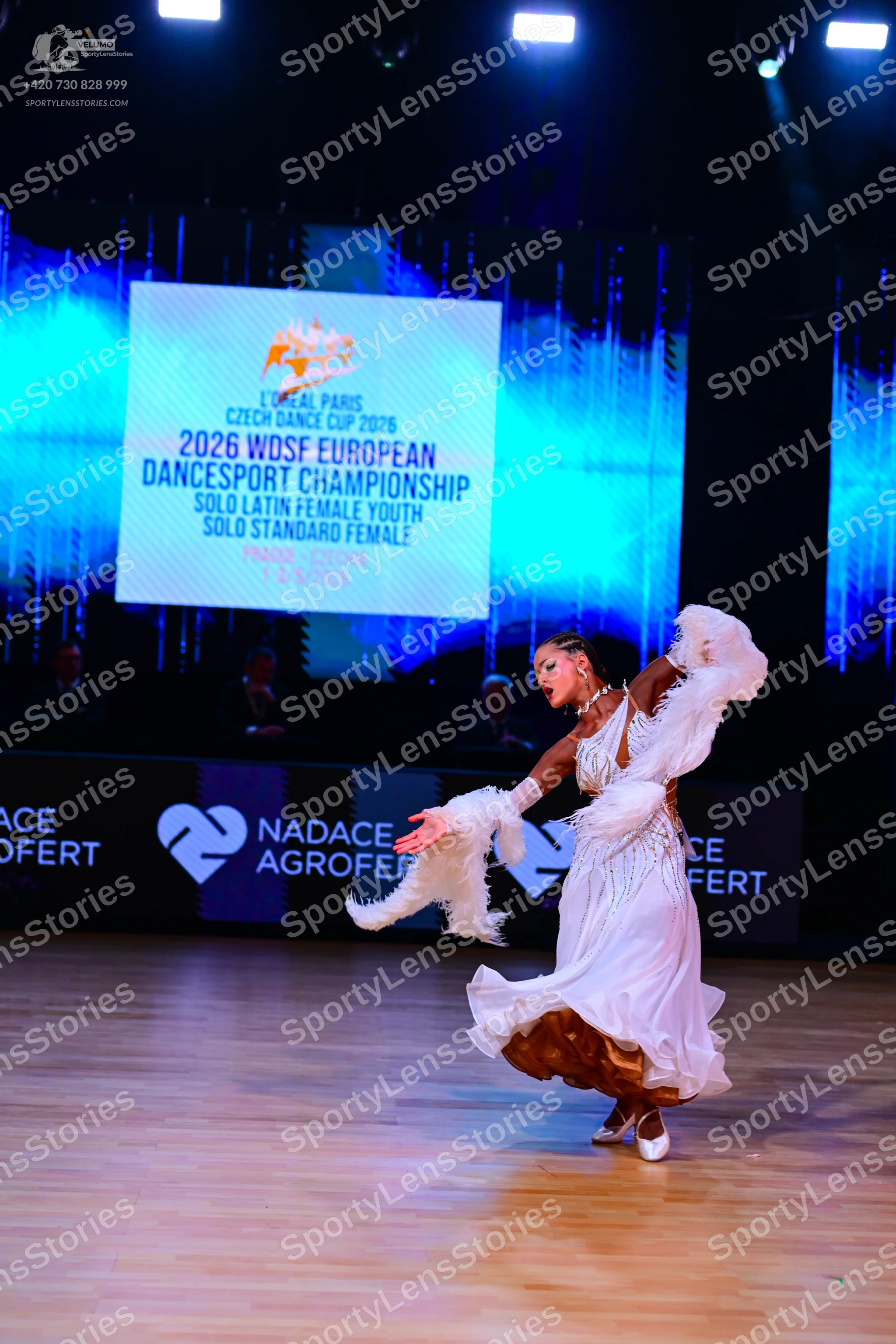 Dancesport competitor: Female dancer: white ballroom dress with a voluminous skirt, sheer or lace detai