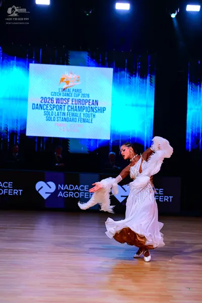 Dancesport competitor: Female dancer: white ballroom dress with a voluminous skirt, sheer or lace detai