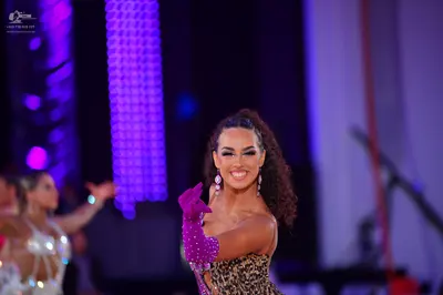 Dancesport competitor: Female dancer in foreground: leopard print latin dress with long magenta sequine