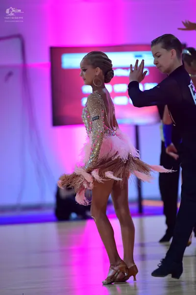 Dancesport competitor: Female dancer: beige sequined Latin dress with a voluminous pink and beige feath