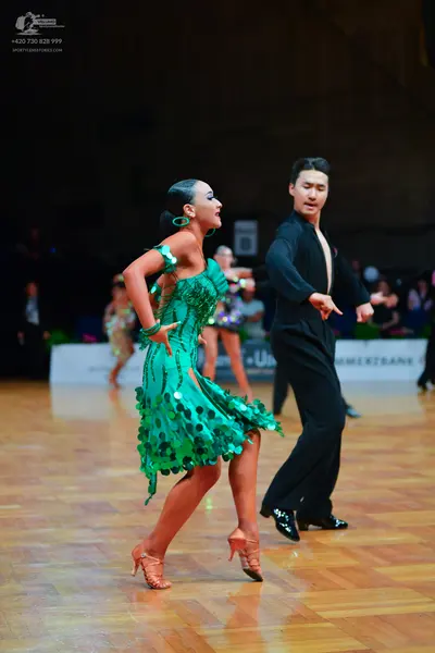 Dancesport competitor: Female dancer: green Latin dress decorated with large green sequins or discs, pa