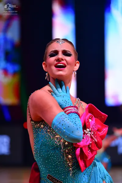 Dancesport competitor: Female dancer: teal latin dress covered in sequins and rhinestones, featuring a 