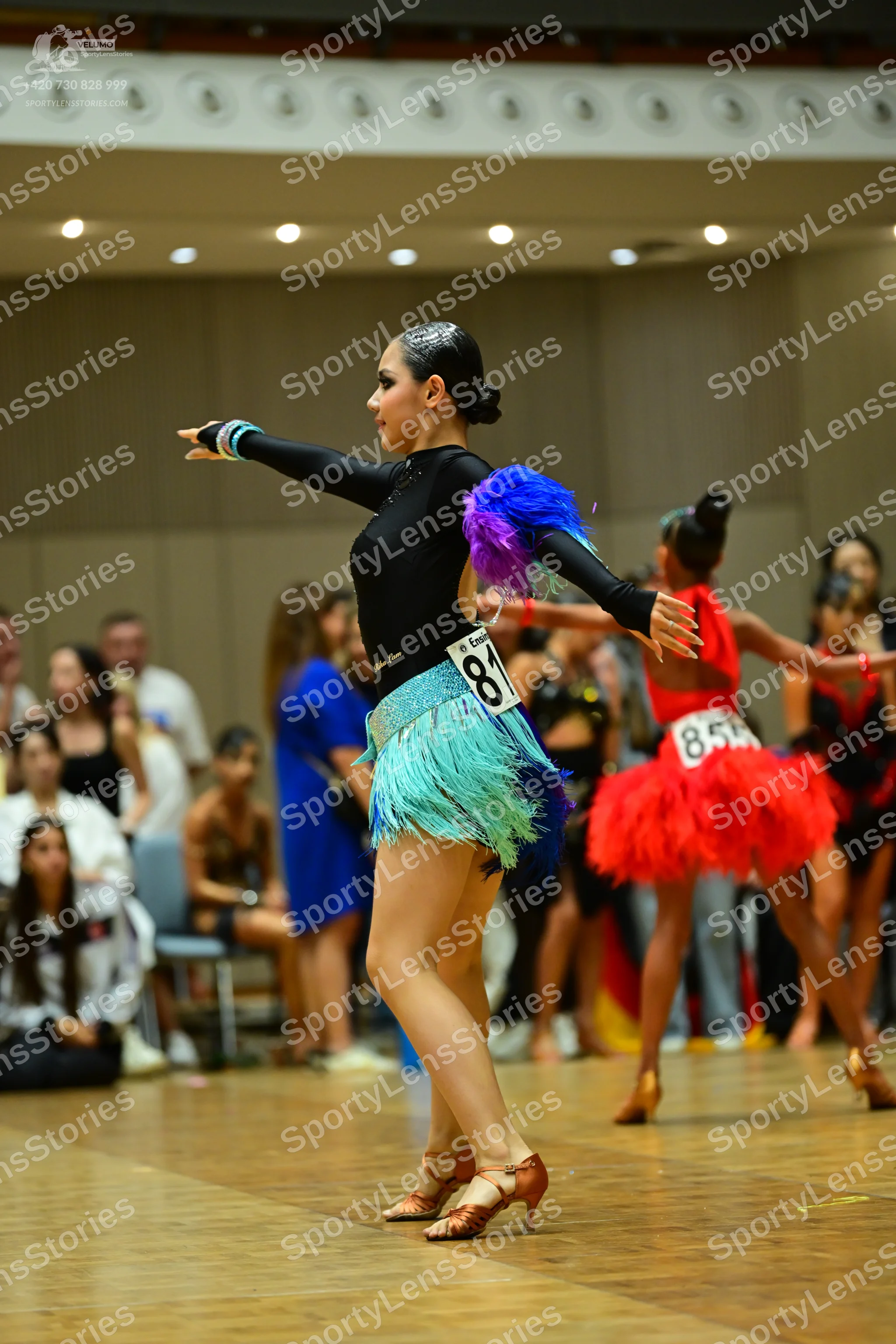 Dancesport competitor #81, #85: Female dancer 1: black long-sleeved Latin dress with a teal fringe skirt and seq