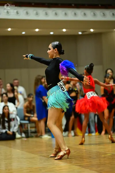 Dancesport competitor #81, #85: Female dancer 1: black long-sleeved Latin dress with a teal fringe skirt and seq