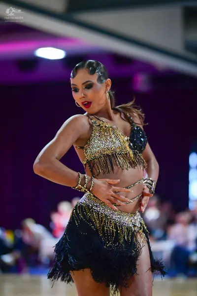 Dancesport competitor: Female dancer: gold and black sequin two-piece Latin costume with fringe