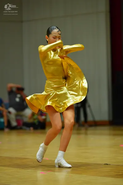 Dancesport competitor: Female dancer: metallic gold long-sleeved latin dress with a flared skirt
