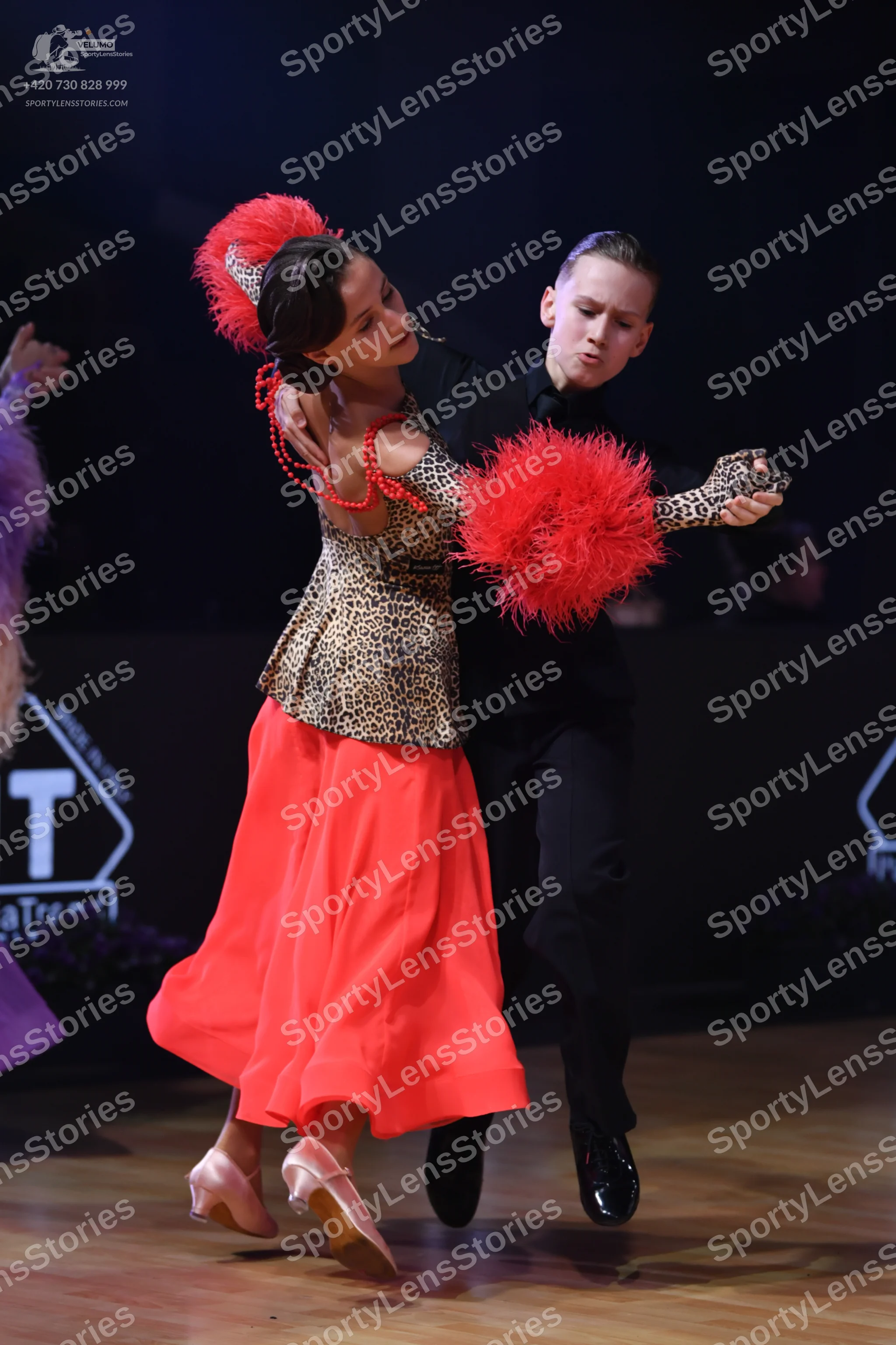Dancesport competitor: Female dancer: leopard print bodice with a long, flowing red skirt, a large red