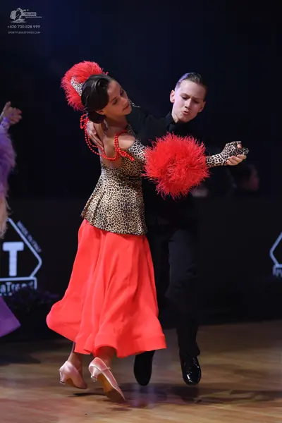 Dancesport competitor: Female dancer: leopard print bodice with a long, flowing red skirt, a large red 