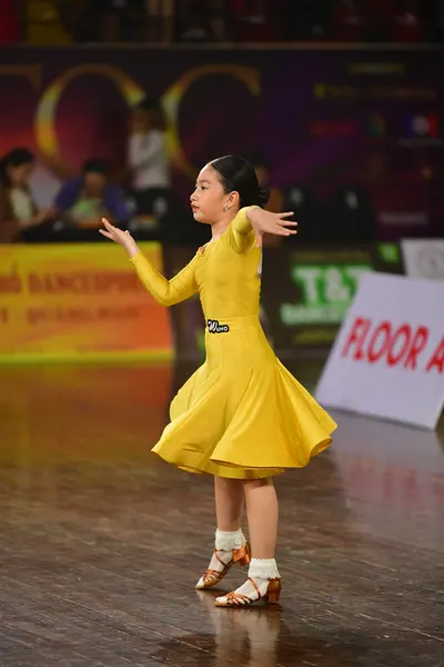 Dancesport competitor: Female dancer: bright yellow long-sleeved dress with a flared skirt
