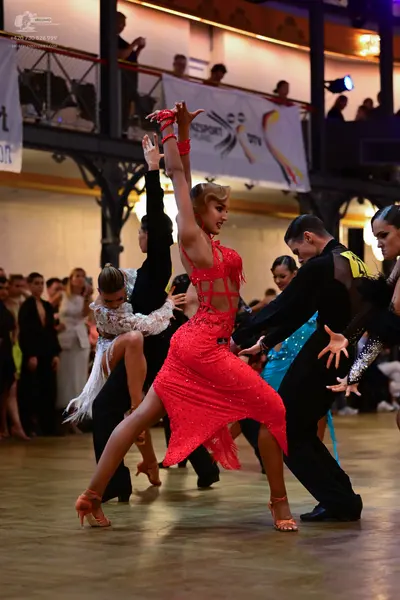 Dancesport competitor: Female dancer in center: red Latin dress with sequins and sheer mesh details