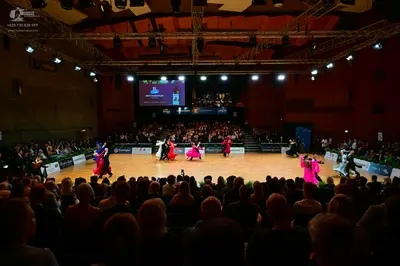 Dancesport competitor: Male dancers: several in black suits; one in a white shirt or jacket with black 