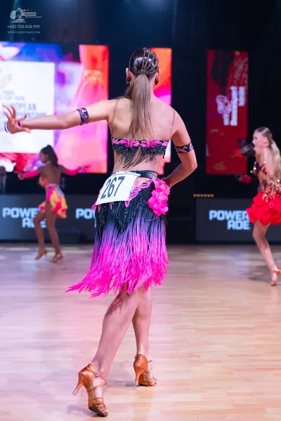 Dancesport competitor: Female dancer (foreground): black and pink Latin dress with sequins, pink floral