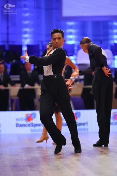 Dancesport competitor: Male dancer in foreground: black Latin dance shirt with a large white textured o