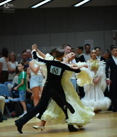 Dancesport competitor #90: Male dancer (foreground): black long-sleeved top with white feather-like trim on