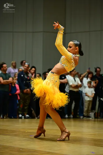 Dancesport competitor: Female dancer: yellow Latin dance costume, consisting of a long-sleeved crop top