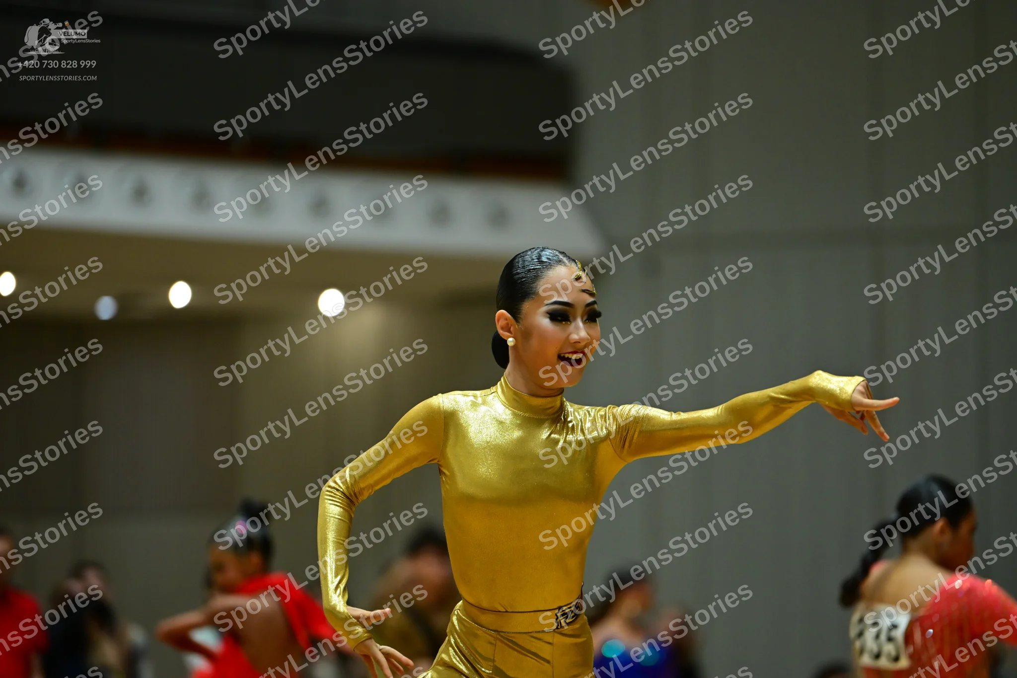 Dancesport competitor #835: Female dancer in foreground: gold metallic long-sleeved bodysuit