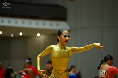 Dancesport competitor #835: Female dancer in foreground: gold metallic long-sleeved bodysuit