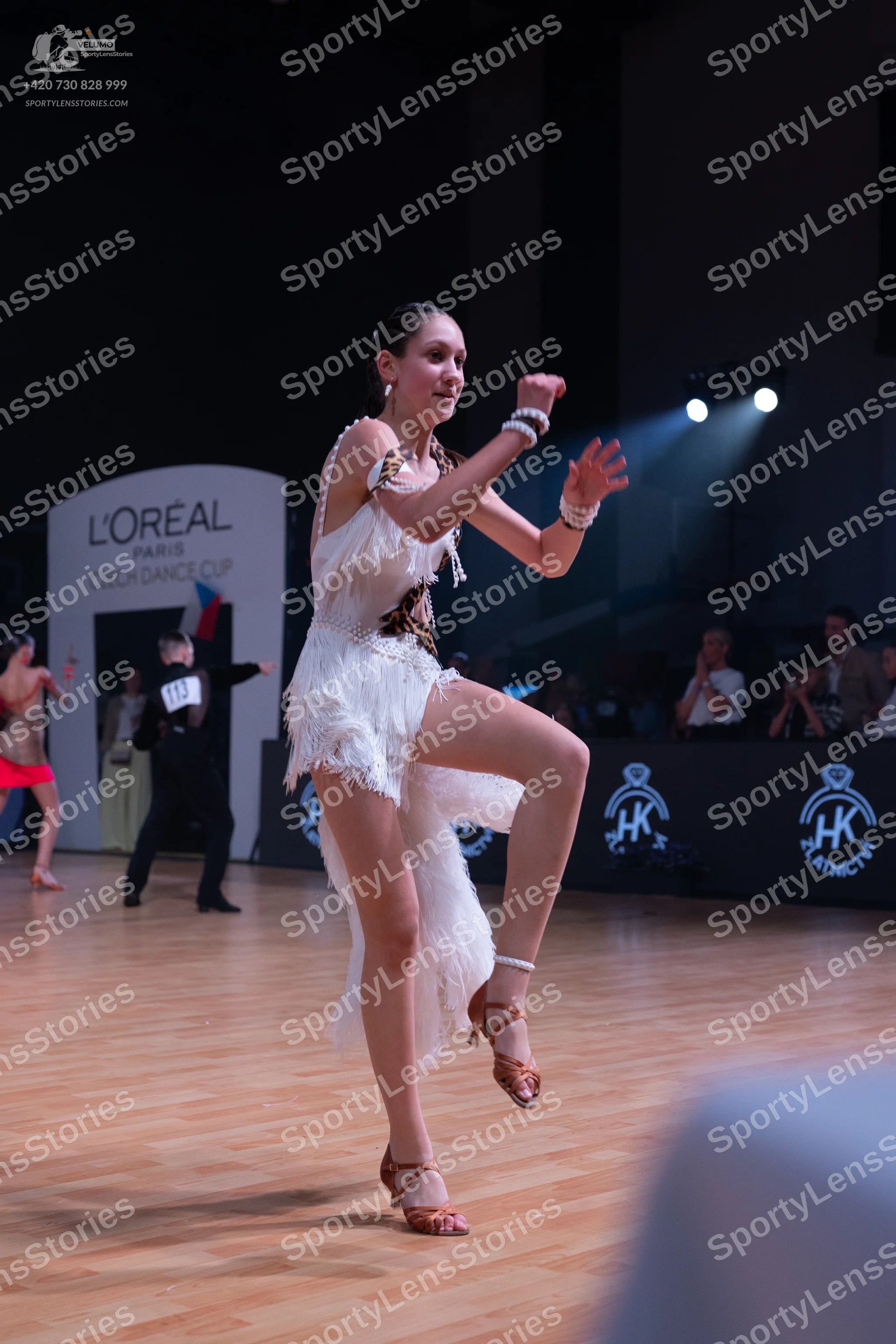 Dancesport competitor: Female dancer: white Latin dance dress with fringe and bronze-colored embellishm